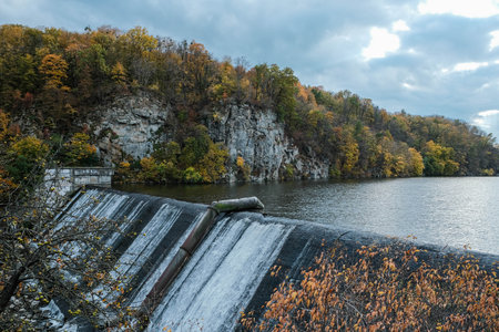 Experience breathtaking autumn beauty with a stunning waterfall and majestic steep cliffsの写真素材