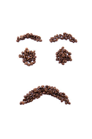 Emoticon face made of coffee beans on white backgroud with copyspaceの写真素材