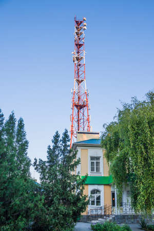 Fragment of a telecommunications tower against a blue sky with snow-white clouds. Radio and satellite pole. Communication technology. Telecommunication industry. Mobile or telecom 4g network. Antenna on blue sky.の写真素材