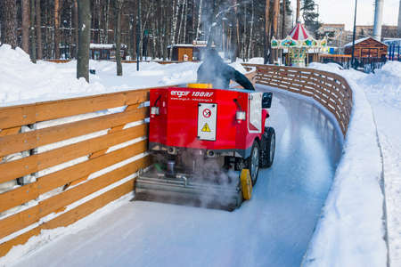 City Park, Balashikha, Russia - February 19, 2021. The process of polishing ice on the ice rink. An ice cutter in action makes an ice rink in a city park.のeditorial素材