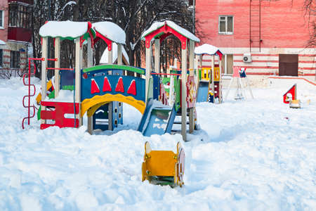 The playground in the city's residential courtyard is built for the development and entertainment of children. The playground is covered with snow during the winter season.の写真素材