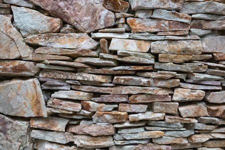 Texture of a stone. Old stone wall texture background. Gray stone wall as a background or texture. Stone wall of natural stones in different sizes. Side covering with natural stones.の写真素材