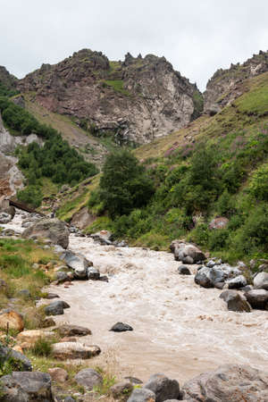 Close-up of a large turbulent flow of water in the river. A mountain river carries its waters posing a danger to careless actions.の写真素材