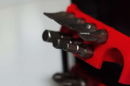 Bits holder in box and many tool bits on white background. Close-up view. Red element in plastic box.の写真素材