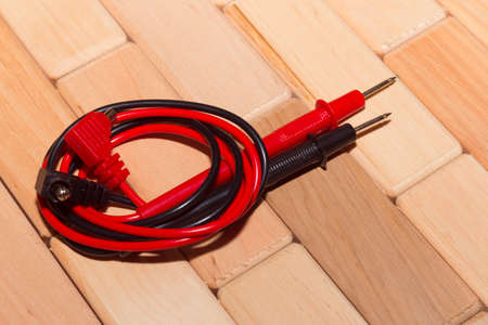 probes of a digital multimeter on the floor of wooden planksの写真素材