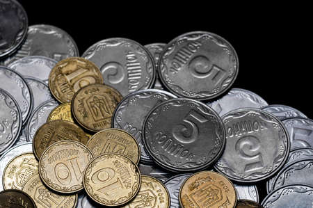 Ukrainian coins isolated on black background. Close-up view. Coins are located below the center of...