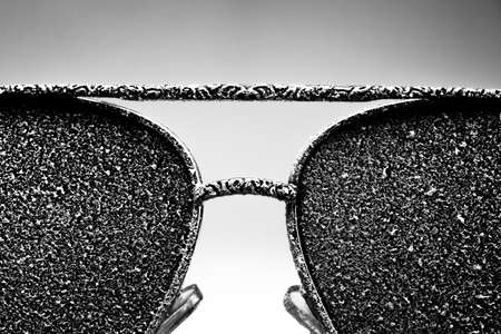 Sunglasses with artificial snow on white-purple background close-up view. Monochome black and white image.の写真素材