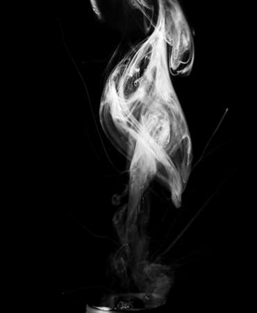 Vape smoke clouds isolated on black background. Hot vape liquid splash in vape coil. Nice aromatic cloud. Low light black and white monochrome photo. Underexposed photo in a low key style.の写真素材