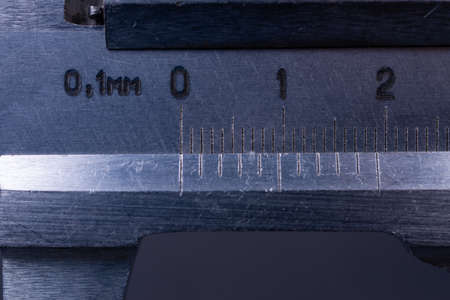 Vintage steel caliper tool closeup. Scale in focus. Tool in very good condition. Scale in metric units, milimeter step. Stock photo on blurred gray background.の写真素材