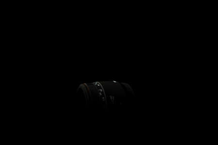 Underexposed photo of DSLR lens. Stock photo isolated on black background. Low light photo. A large...