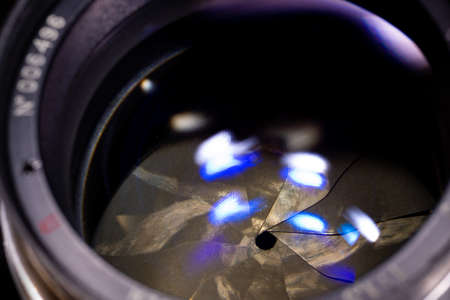 Lens aperture low light photo closeup. Blue traces on glass. Aperture blades is dirty and partially...
