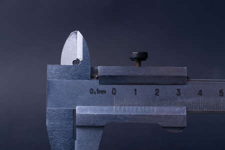 Vintage steel caliper tool closeup. Caliper tips and scale in focus. Tool in very good condition. Scale in metric units, milimeter step. Stock photo on blurred gray background.の写真素材