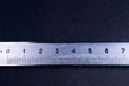 Vintage steel caliper metric scale on dark background. Scale in focus. Tools in very good condition. Stock photo on blurred dark gray background.の写真素材