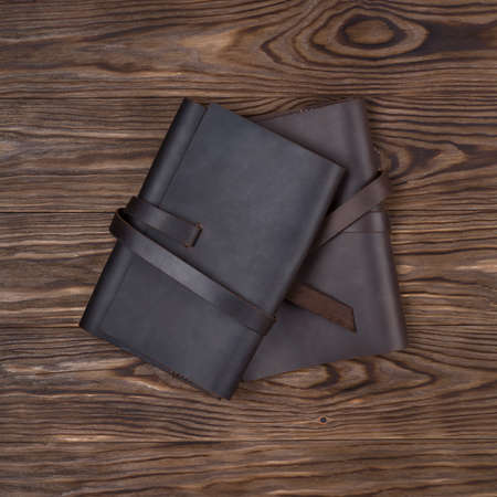 Black and brown handmade leather notebook covers on wooden background. Stock photo of luxury...