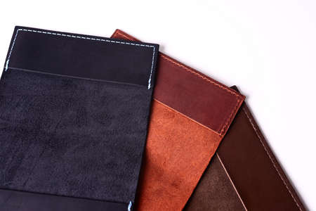 Three handmade leather passport covers isolated on white background. Closeup view. Covers are dark...