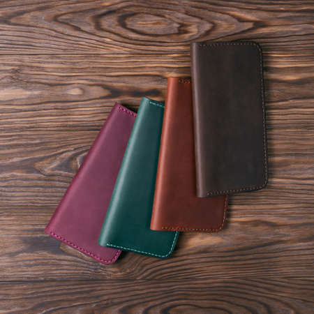 Four handmade leather porte-monnaie on wooden textured background. Up to down view. Stock photo of...