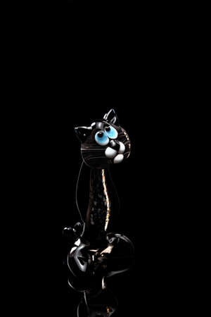 A fugurine of transparent black cat isolated on black background. Stock photo of glass handmade figurine.の写真素材