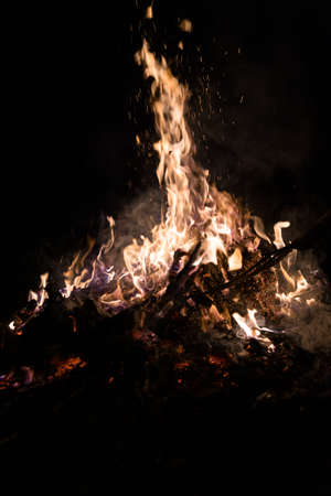 A low light underexposed photo of burning fire. Many sparks and flames. Burning books and wood. の写真素材