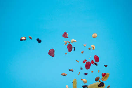 Dried and candied fruits and nuts flying on blue background. Stock photo of healty and nutrient food. Conceptual photo of vegan and vegetarian healty food.の写真素材