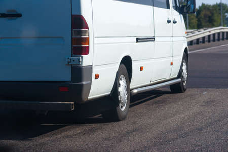 Side view of white passenger bus on the sunny road.