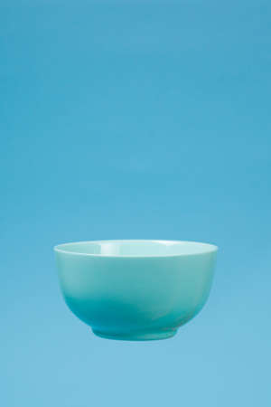 A blue ceramic mattle deep bowl for breakfast flying on blue background. Ideal photo for levitation of food and fruits or nuts.の写真素材