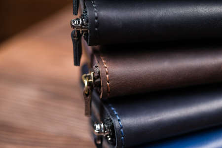 A stack of handmade leather wallets on wooden blurred background. Close up view.の写真素材