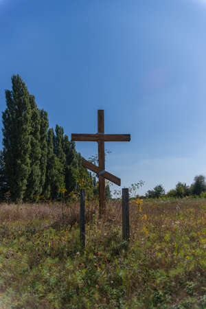 A wooden cross in the middle of the field. Christian symbol.の写真素材