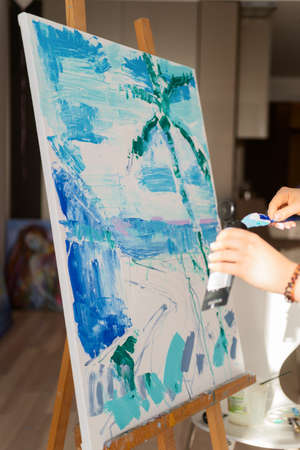 Woman paints a picture on canvas in her living roomの写真素材