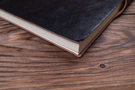 A part of black gloss formal daily planner on old wooden background. Branding mockup.の写真素材
