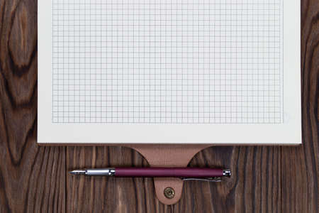 Open daily planner on wooden background with fountain pen. Copyspace template and branding mockup.の写真素材