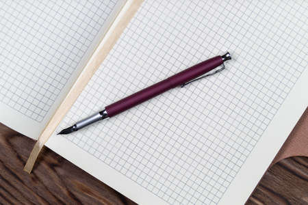 A part of open daily planner on wooden background with purple fountain pen. Copyspace template and branding mockup. Ready to write text.の写真素材