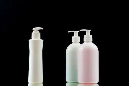 Plastic dispencer with liquid soap on a black background. Closeup