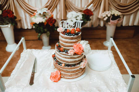 the main wedding cake, decorated with strawberries, is on the table with the plates and knifeの写真素材