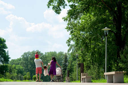 Happy family of four people walking on the city park in the summer sunny dayの写真素材