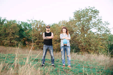 young guy in a cap and solar oskah, with a beard and mustache, and tattooed, with his pregnant girl in dreadlocks, outdoors in the fall posing at the camera,の写真素材