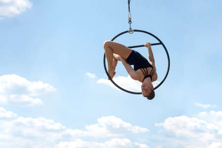 Sport woman doing exercises with a hoop, outdoor, against the blue sky. Sports equipment and lifestyle concept. Antigravity yoga.の写真素材
