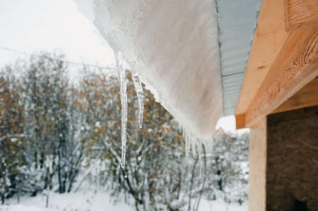 Snowdrift on the roof after a snow, icicles and frost, snow melt from the roof, dangerの写真素材