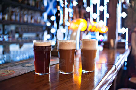 three varieties of freshly brewed natural beer on a dark pubの写真素材