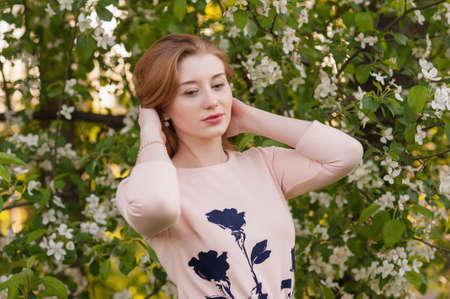 Beautiful Woman Fashion Model with Spring Blossoms Background Spring Beauty Woman with Apple Tree Flowers. Skin and hair careの写真素材