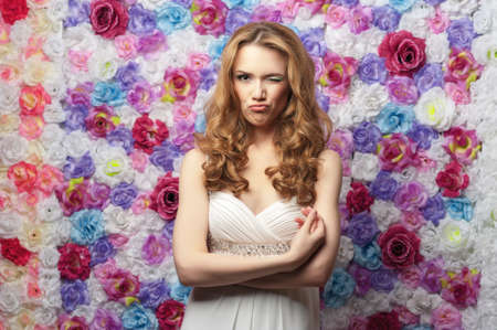 Beautiful smiling woman wearing a wedding dress on a background of flowers. Emotional playfulの写真素材