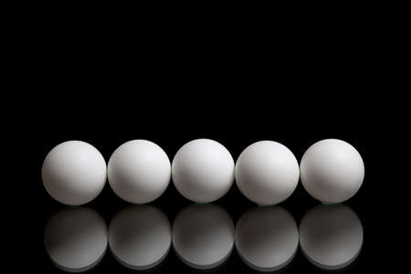 Five balls for ping pong in a row on a dark backgroundの写真素材