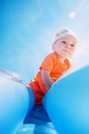 A smiling boy playing on the beach with an inflatable, air mattress. Hot summer day