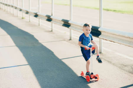 Little boy on a scooter in a city park, outdoorsの写真素材