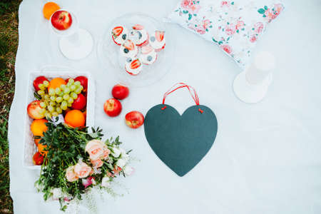 Picnic on the glade for lovers with fruit and cakes, black chalkboard in the form of a heart, a love storyの写真素材