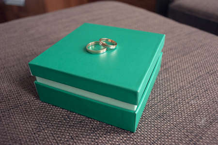 Wedding rings for the newlywed couple lie on a light green boxの写真素材