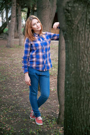 Portrait of a beautiful girl. smiling, posing on camera. in a blue shirt in a cage. Against the background of the autumn parkの写真素材