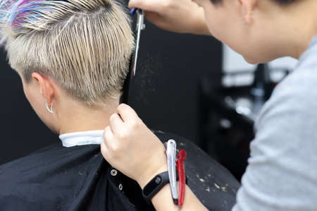 Women's haircut. Hairdresser, beauty salon. Professional hairdresser making stylish haircut. Hairdresser cutting woman bangs hair. Process of hair cutting with use scissorsの写真素材