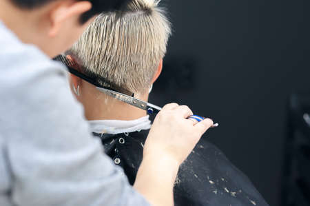 Women's haircut. Hairdresser, beauty salon. Professional hairdresser making stylish haircut. Hairdresser cutting woman bangs hair. Process of hair cutting with use scissorsの写真素材