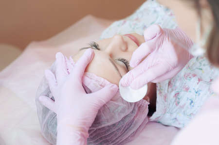 A young woman lies and gets a make-up of her eyebrows in a beauty salon. The use of permanent makeup on the eyebrows. The master works with the eyebrows. Semi-permanent makeup.の写真素材