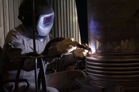 Welder with protective mask welding metal and sparks.の写真素材